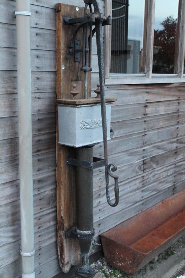 Zeer-mooie-unieke-waterpomp-met-mooie-bak-op-bord.-staat-bij-oude-zagerij