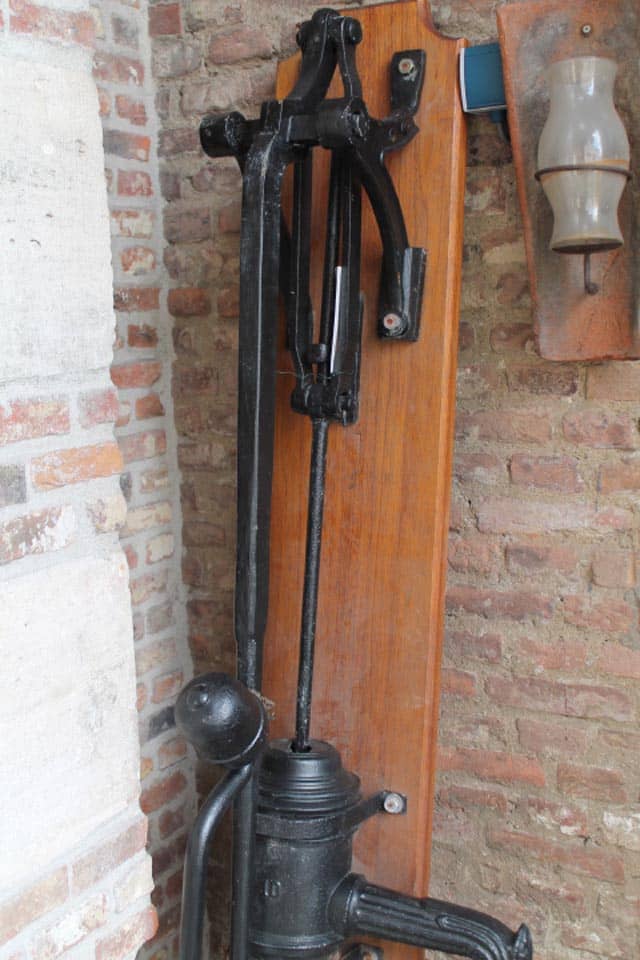 Zwarte-gelakte-waterpomp-op-houten-bord-compleet